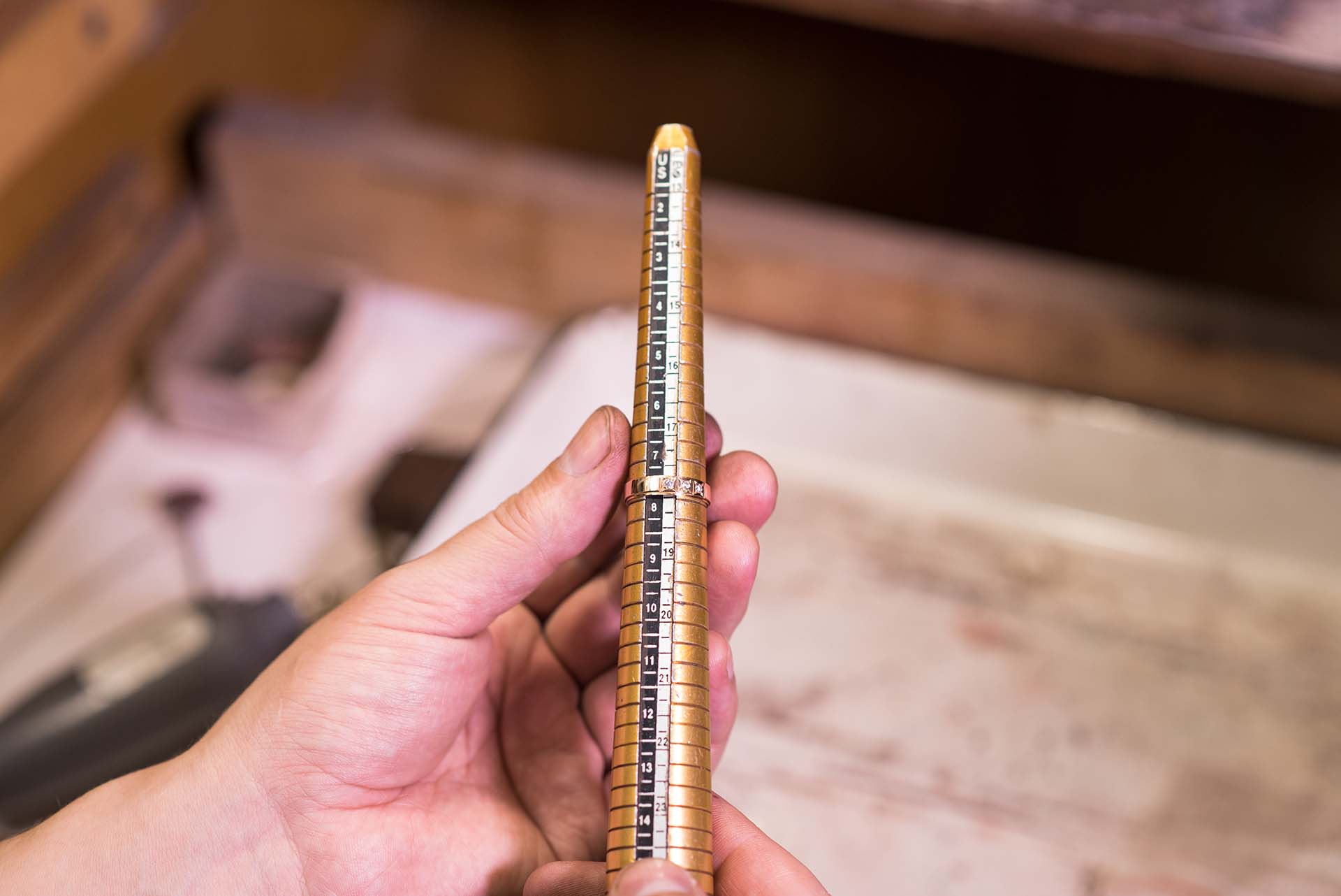 How to Pull Off a Secret Ring Sizing Without Asking Directly Male hands of a jeweler who measures the size of a ring using a ring gauge
